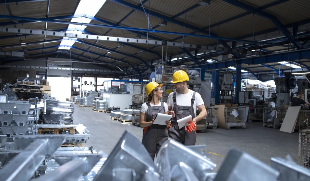 Factory workers in industrial production hall sharing ideas. Factory workers in industrial production hall sharing ideas.