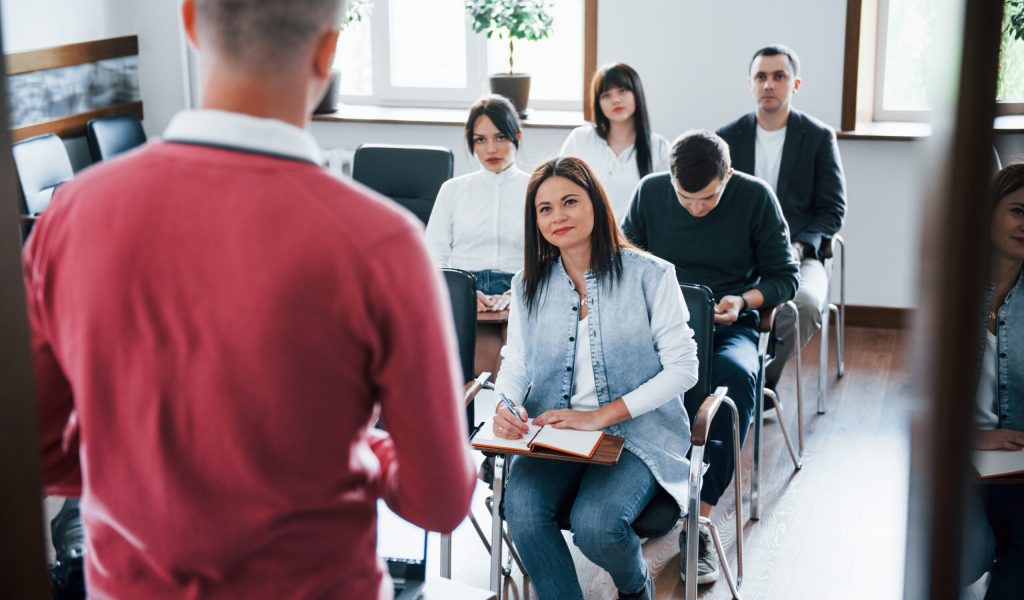 In red shirt. Group of people at business conference in modern classroom at daytime In red shirt. Group of people at business conference in modern classroom at daytime.